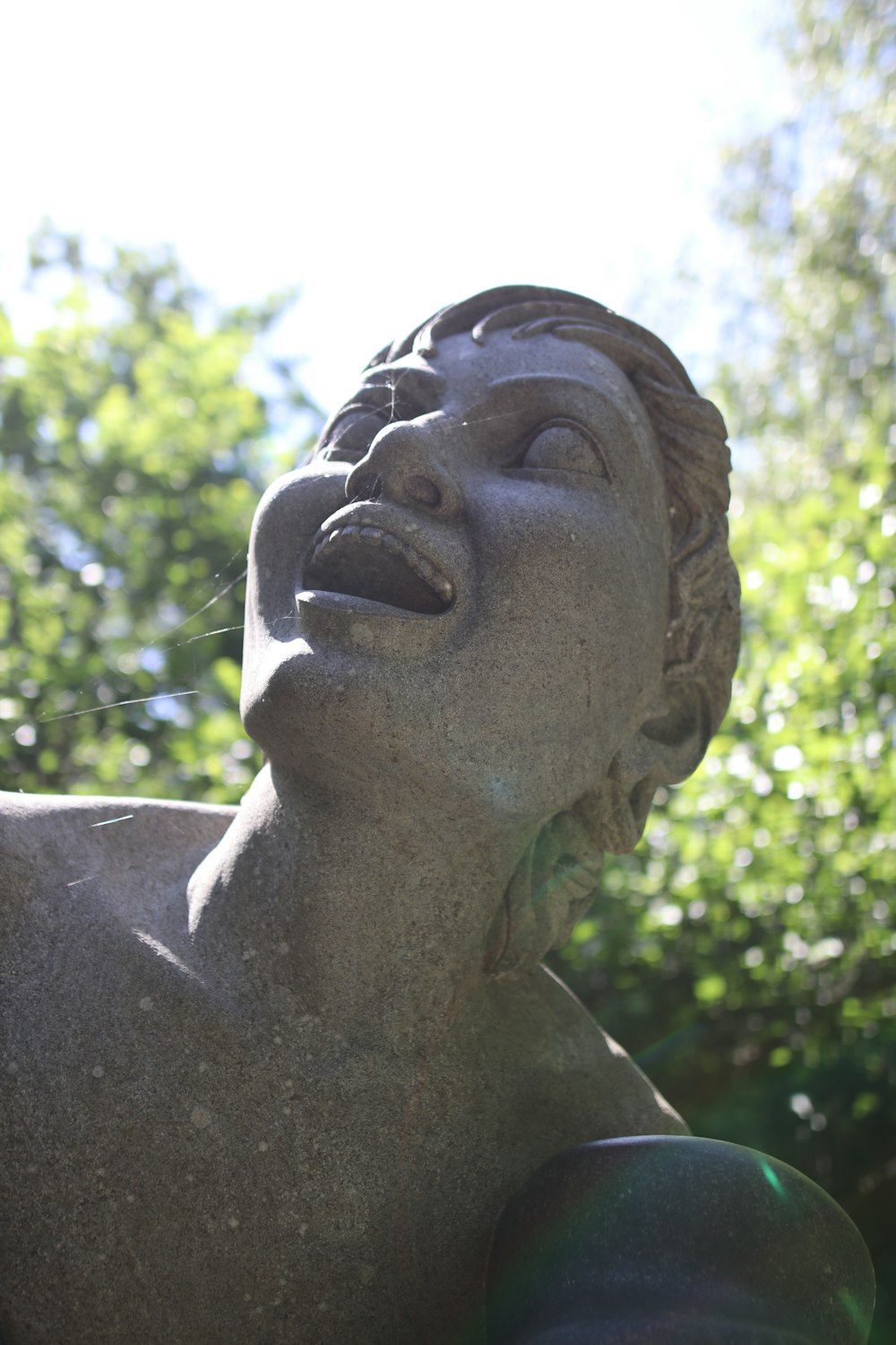 grey concrete statue near green trees during daytime