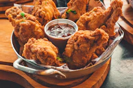 Golden fried chicken pieces arranged on a plate with a tangy dipping sauce.