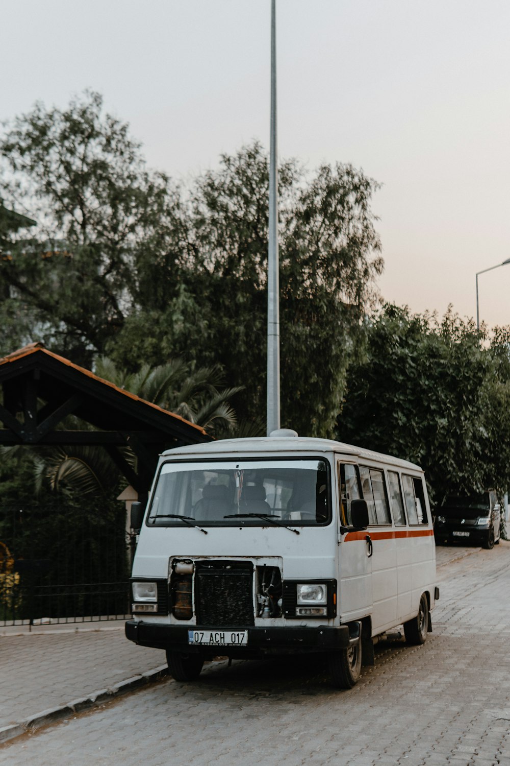 Fourgonnette Volkswagen T-2 blanche et bleue garée près d’arbres verts pendant la journée