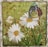 A mosaic artwork featuring a butterfly perched on a daisy flower. The mosaic is composed of multiple small glass pieces forming shapes of white daisies with yellow centers, green grass, and a multicolored butterfly with details in black, orange, yellow, and blue.