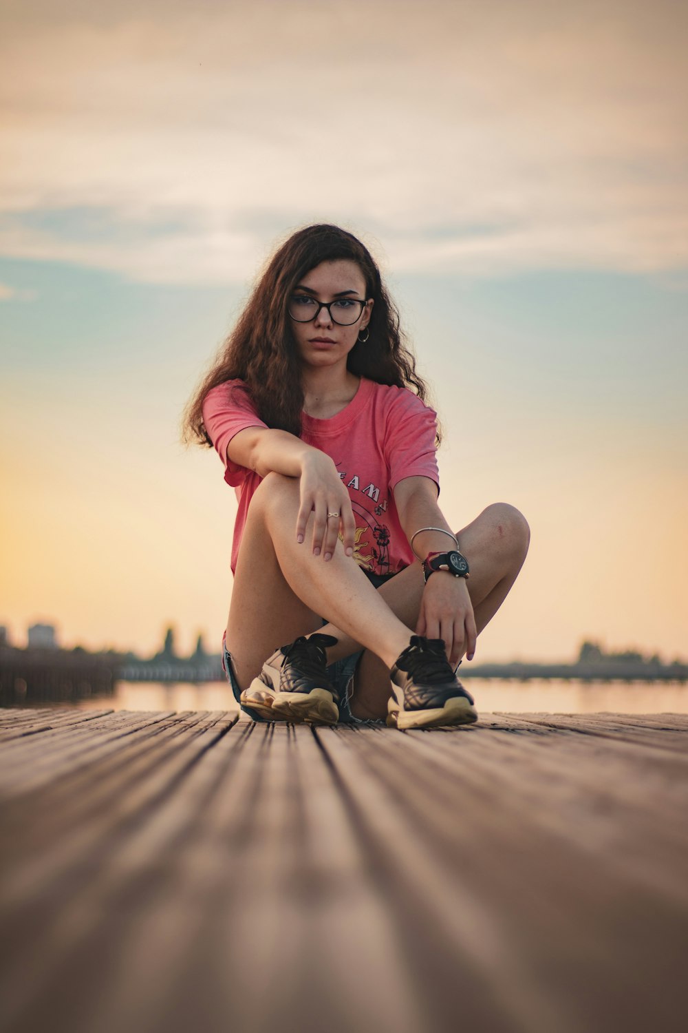 woman in pink t-shirt sitting on brown sand during daytime