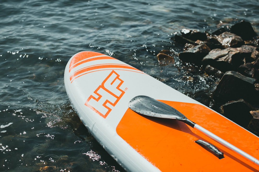 white and orange surfboard on black rock