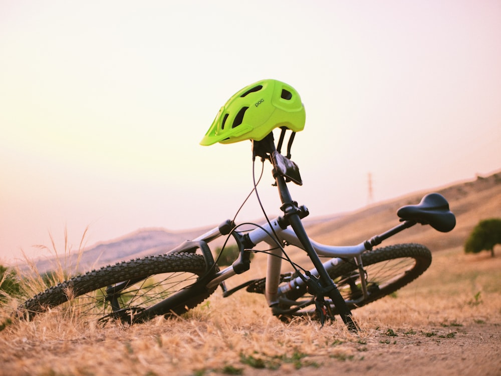 black and green bicycle with green bicycle helmet on brown field during daytime