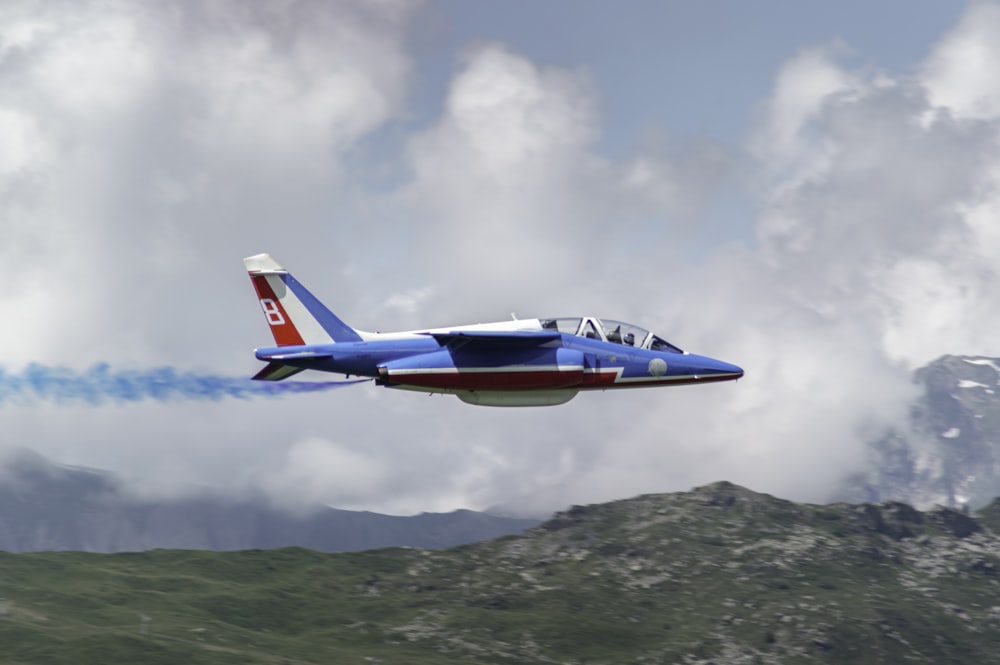 red and white airplane flying over green mountain during daytime