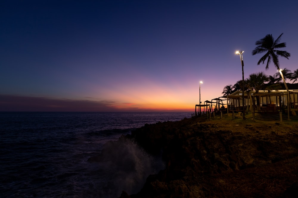 Silueta de personas de pie en la orilla del mar durante la puesta del sol