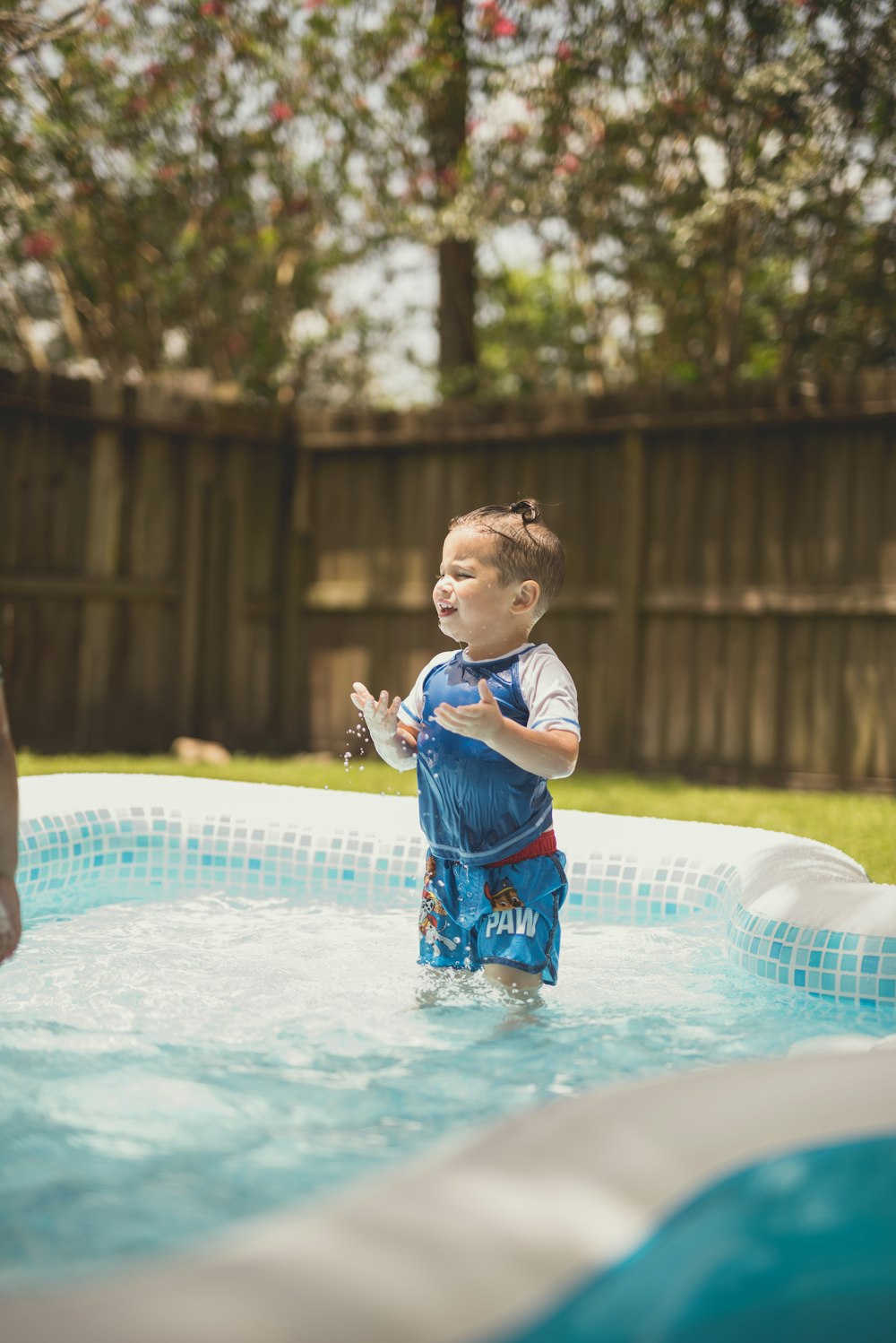 boy in blue and white crew neck t-shirt on swimming pool during daytime