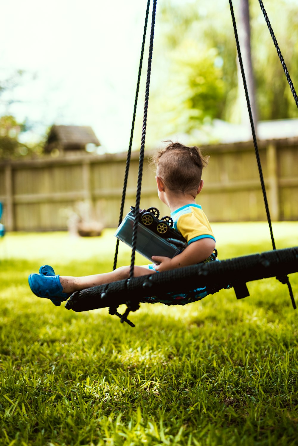 boy in red shirt riding on swing during daytime