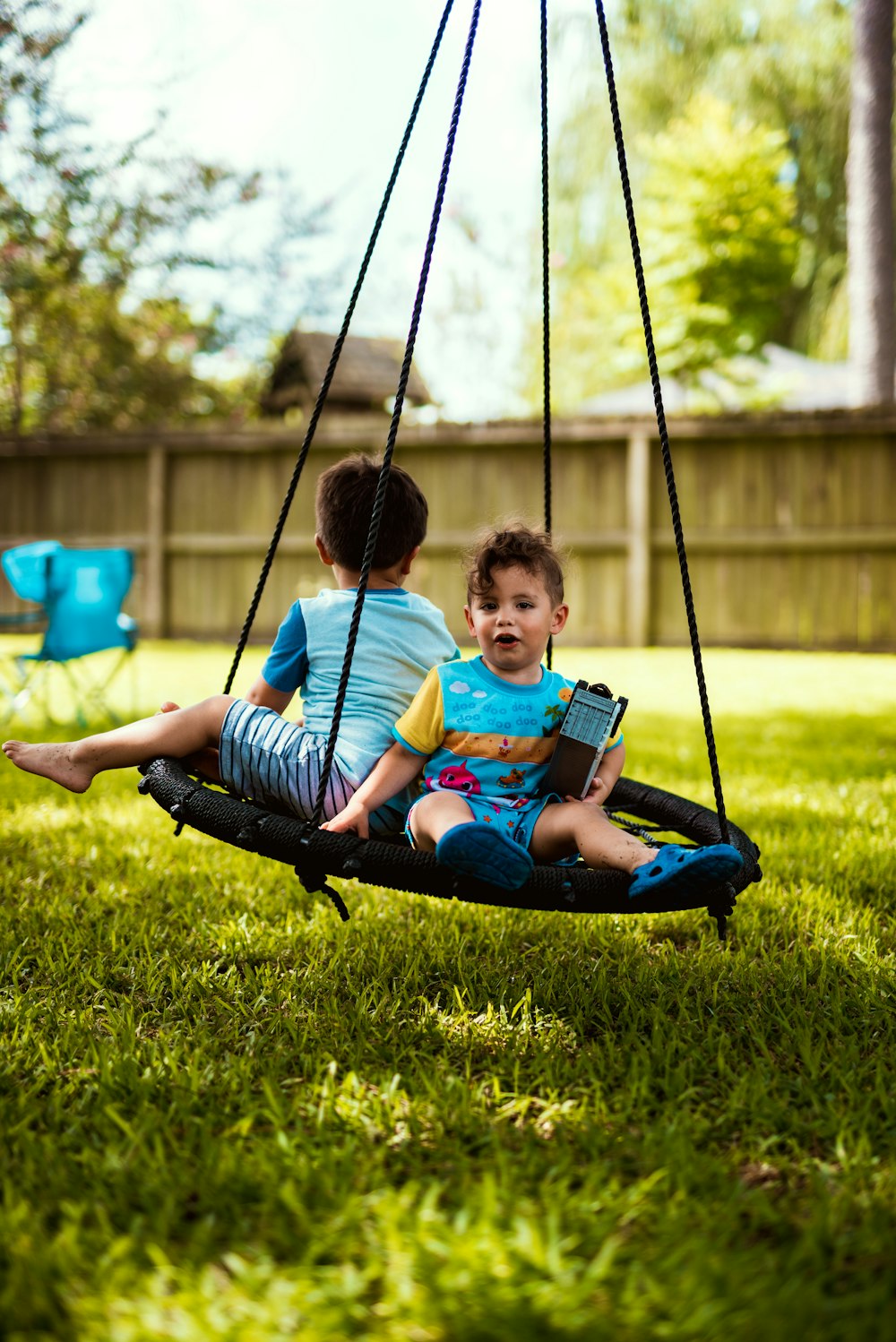 boy in blue and white stripe shirt sitting on swing during daytime