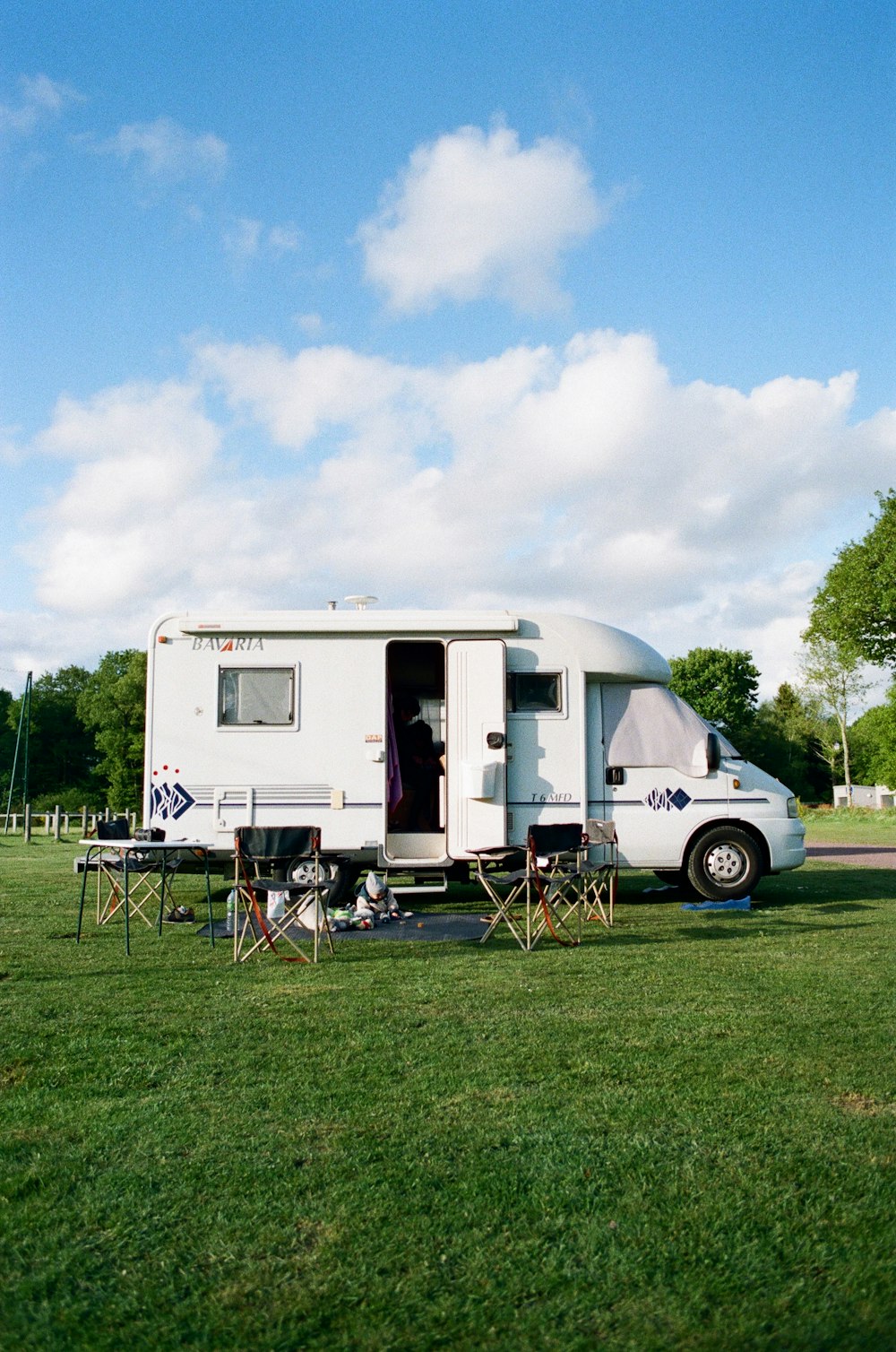 white and brown rv trailer on green grass field under white cloudy sky during daytime