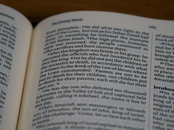 An open book displaying text in English with a focus on biblical content, including headings and body text on both visible pages.