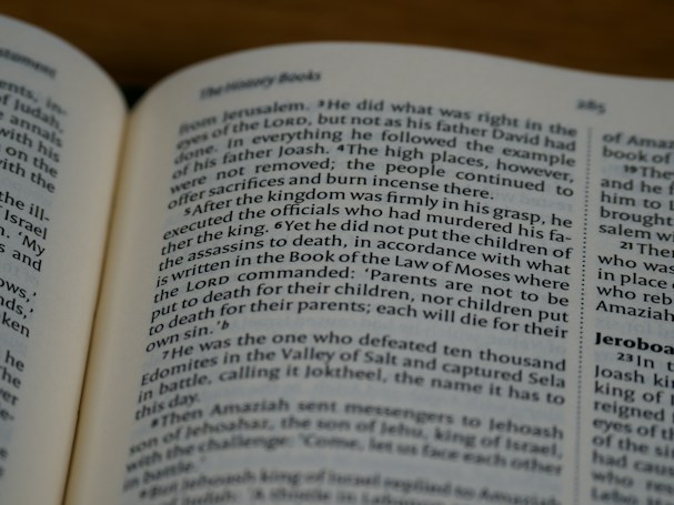 An open book displaying text in English with a focus on biblical content, including headings and body text on both visible pages.