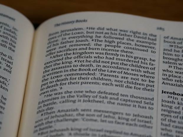 An open book displaying text in English with a focus on biblical content, including headings and body text on both visible pages.