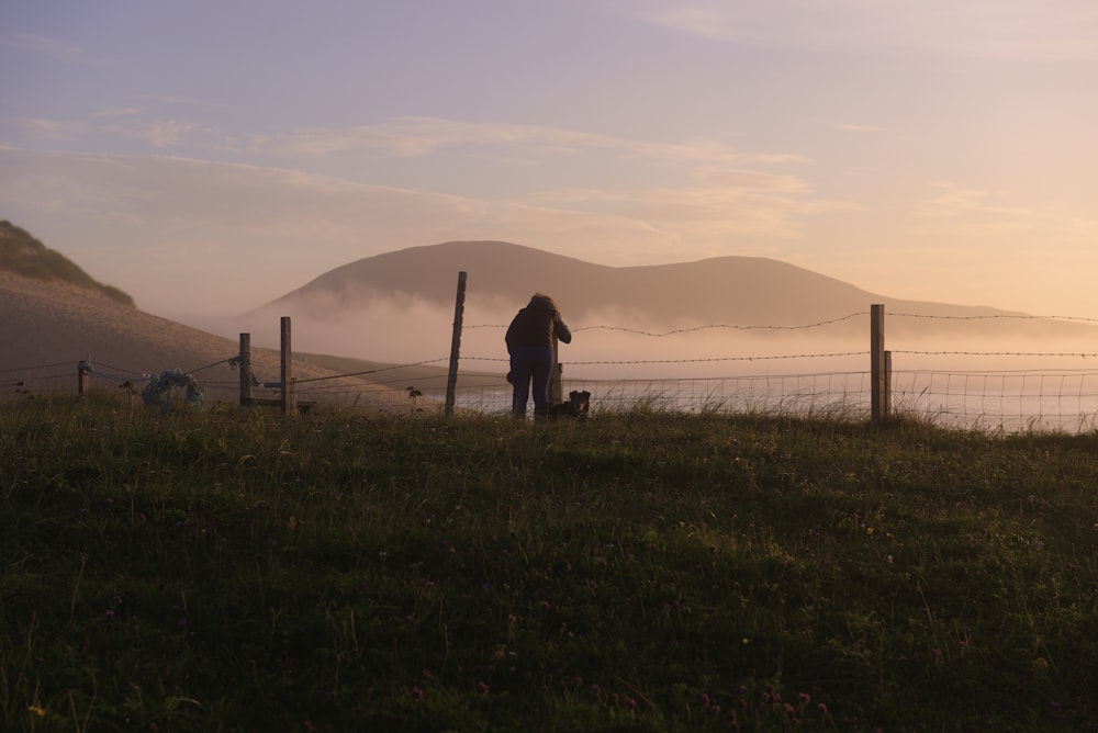 silhouette of man and woman standing on green grass field during daytime