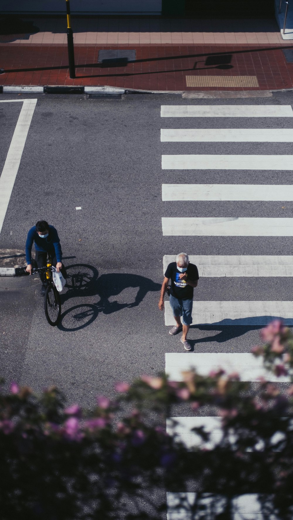 man in black t-shirt and blue denim jeans riding bicycle on pedestrian lane during daytime
