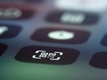 Close-up image of a digital screen displaying app icons, with one prominently featuring a QR code symbol inside a square with rounded corners.