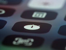A close-up view of a digital device screen displaying several app icons, with a focus on one icon featuring a down arrow inside a circle. The image is slightly blurred, adding an abstract quality.