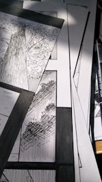 A collection of black and white comic panels featuring detailed illustrations of trees. The scene captures the texture of tree bark and the intricacy of leaves, with strong contrast between light and shadow. A drawing pen lies beside the panels.