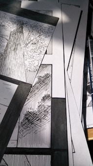 A collection of black and white comic panels featuring detailed illustrations of trees. The scene captures the texture of tree bark and the intricacy of leaves, with strong contrast between light and shadow. A drawing pen lies beside the panels.