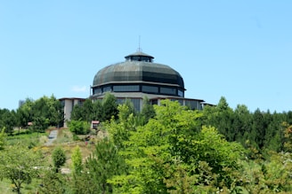 A sleek data center surrounded by lush greenery under clear blue skies, showcasing sustainable technology.
