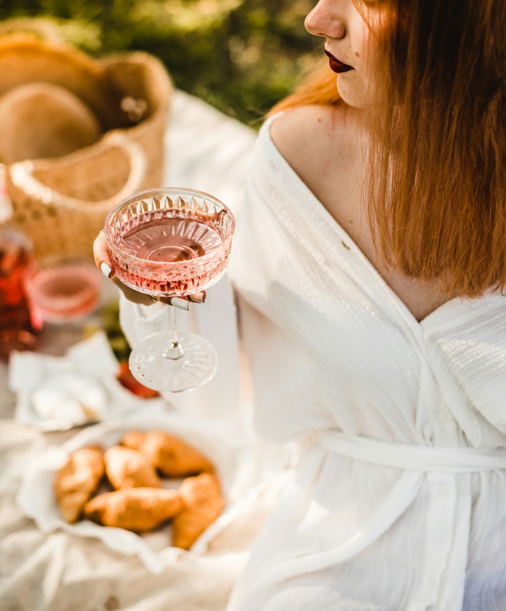woman in white dress holding clear wine glass