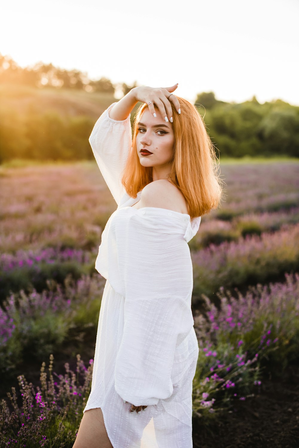 woman in white long sleeve dress standing on purple flower field during daytime