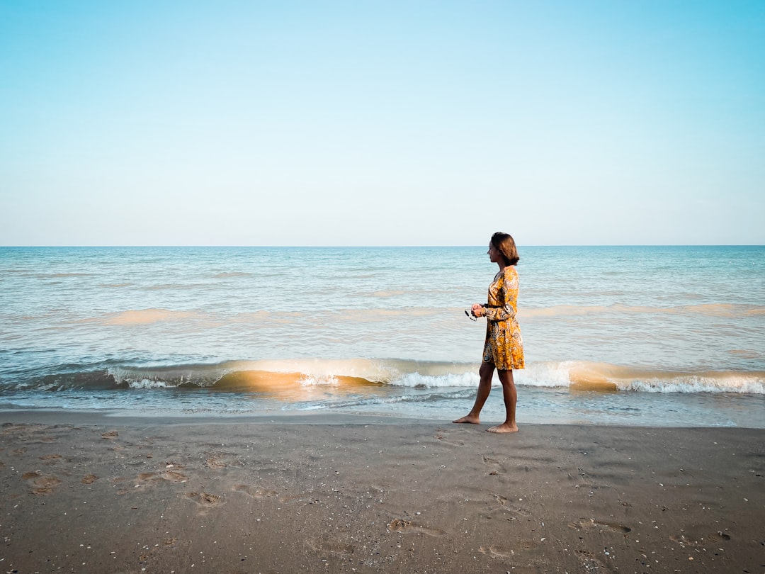 girl in brown dress standing on beach during daytime