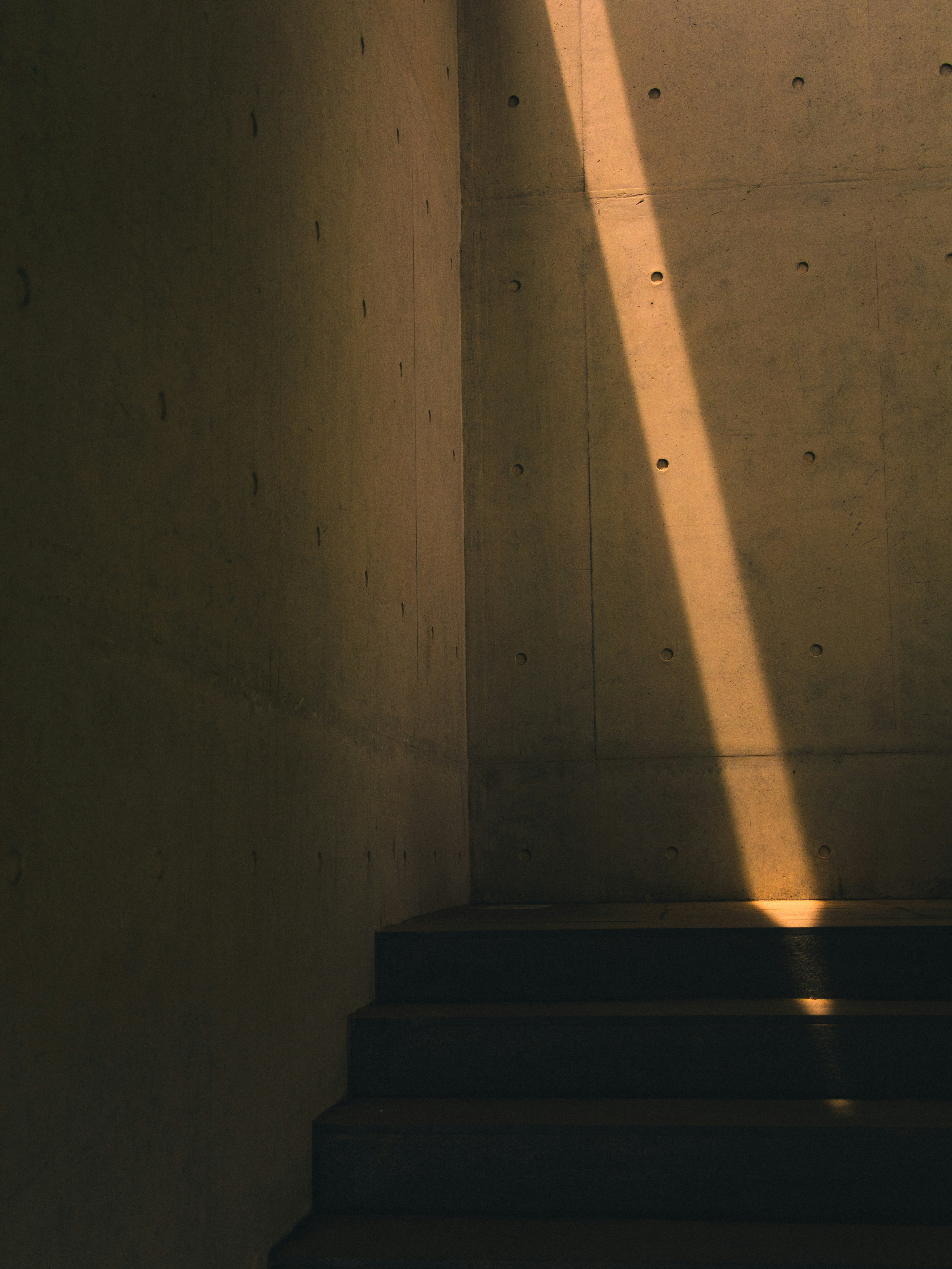 white concrete wall with brown wooden stairs