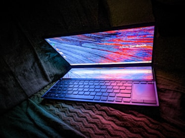 A sleek laptop screen displaying dynamic AI software interfaces with glowing data visualizations.