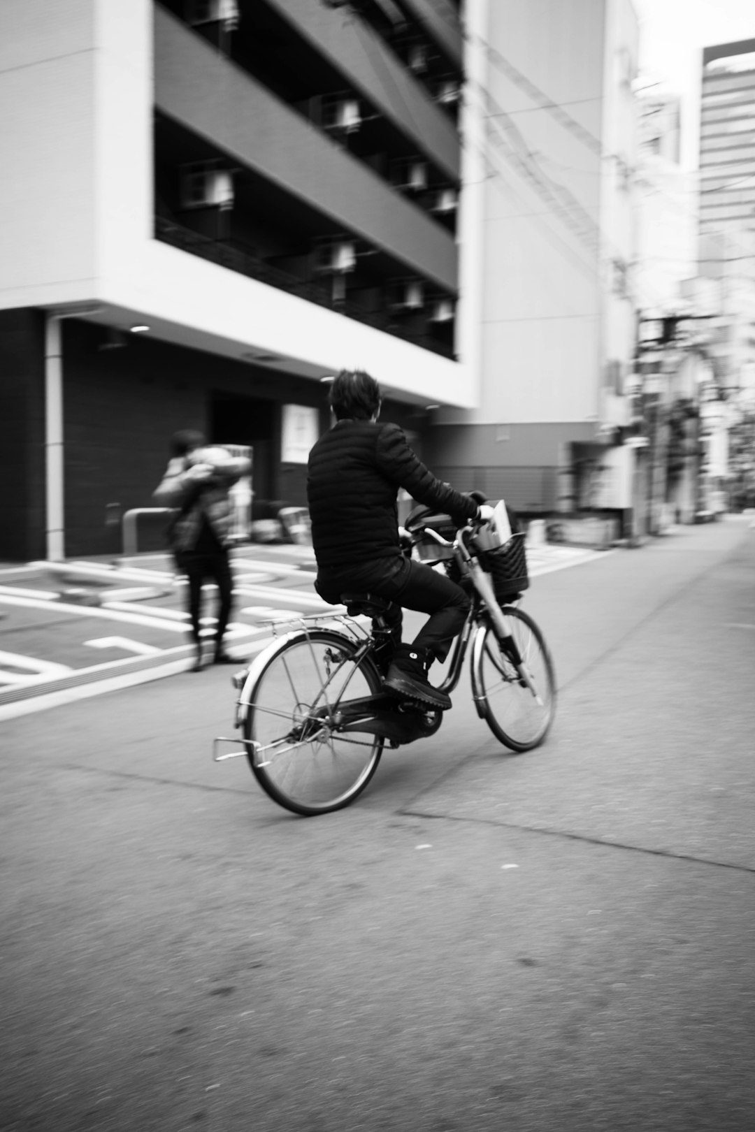 man in black jacket riding bicycle in grayscale photography