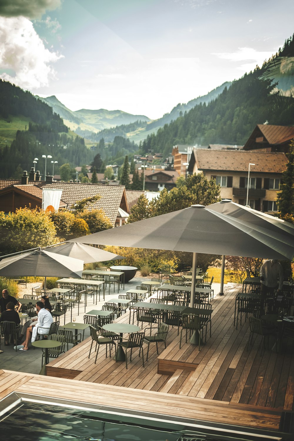 Menschen, die tagsüber auf Stühlen unter weißem Terrassenschirm sitzen