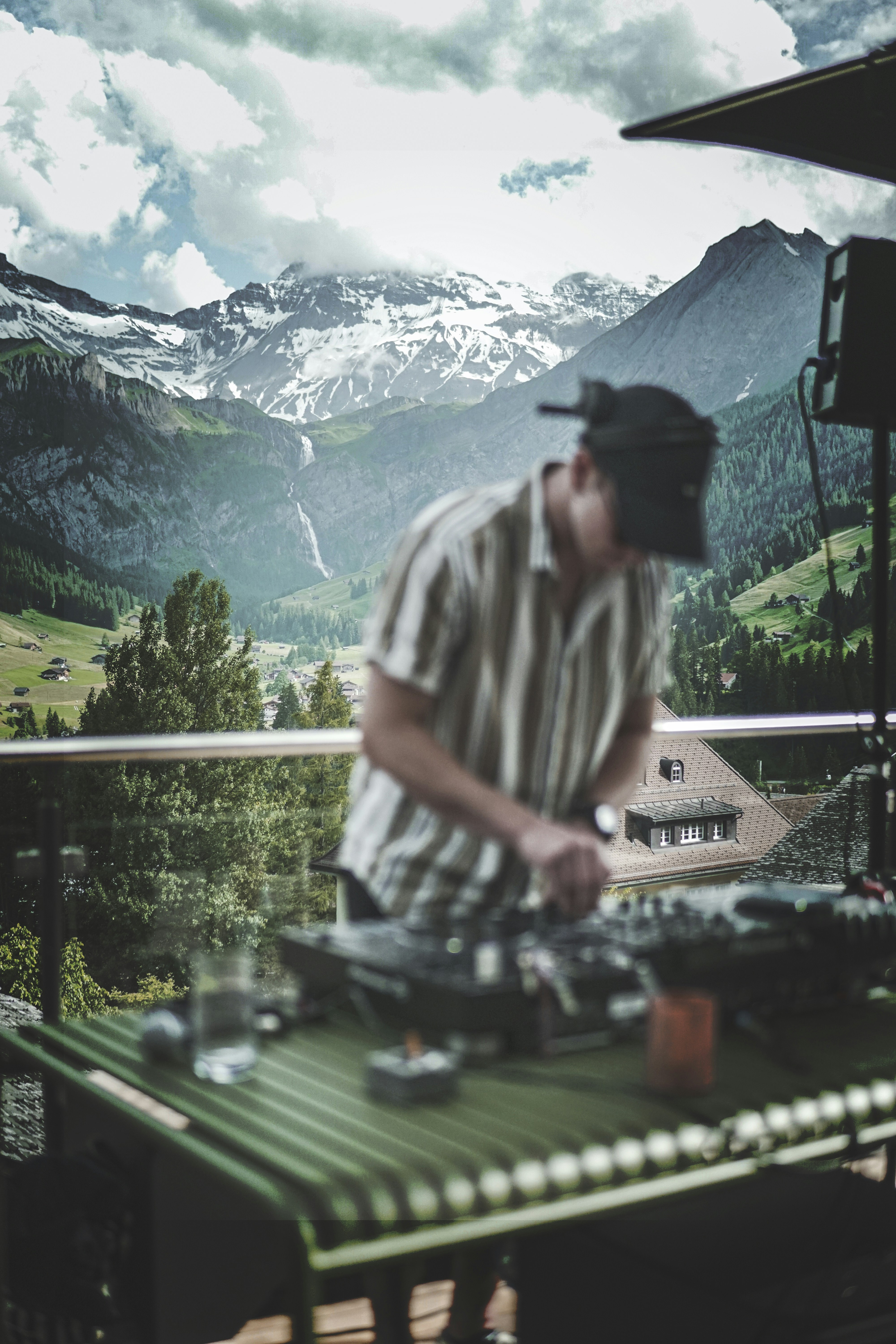 man in white and black stripe shirt standing near green trees and mountains during daytime