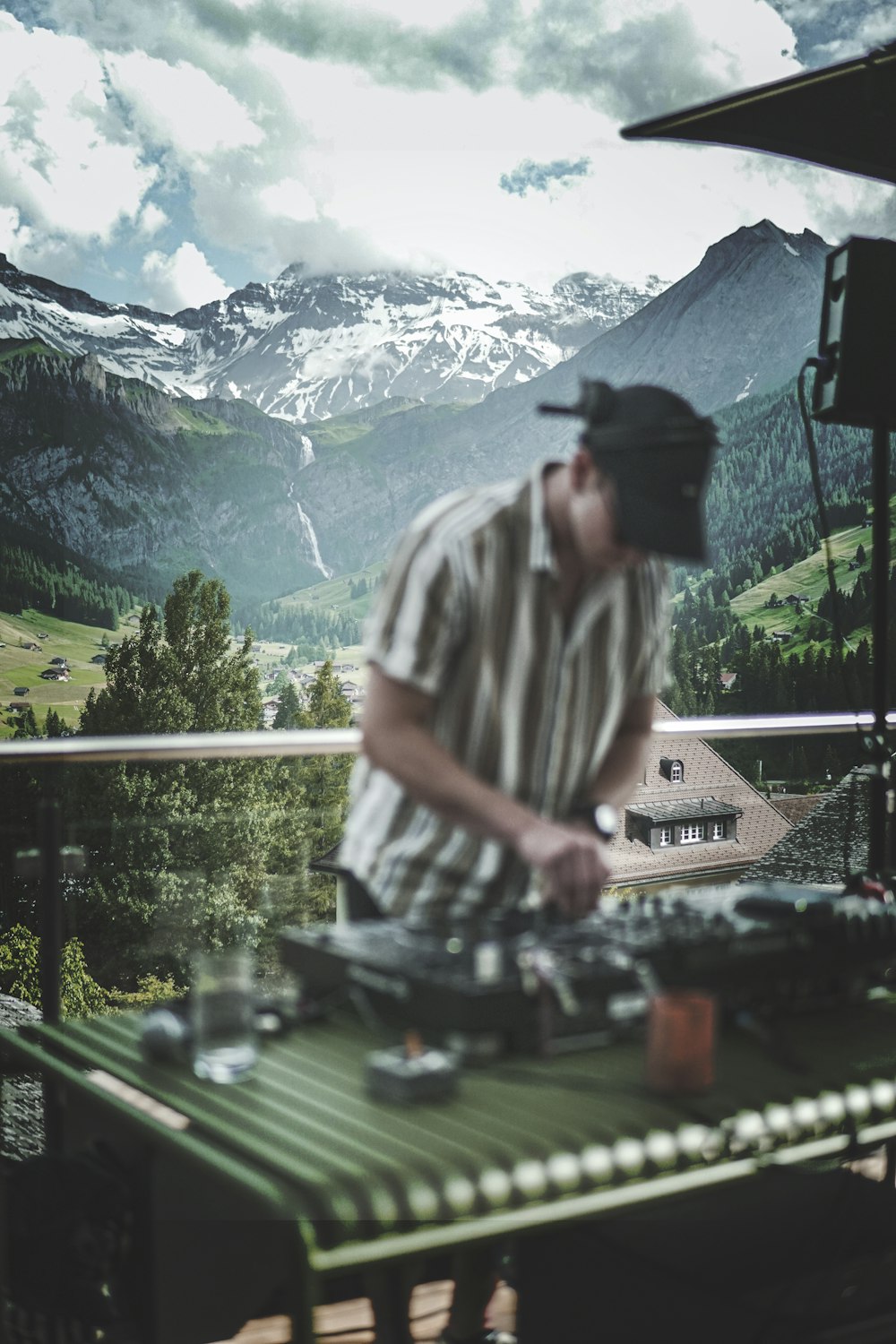 man in white and black stripe shirt standing near green trees and mountains during daytime