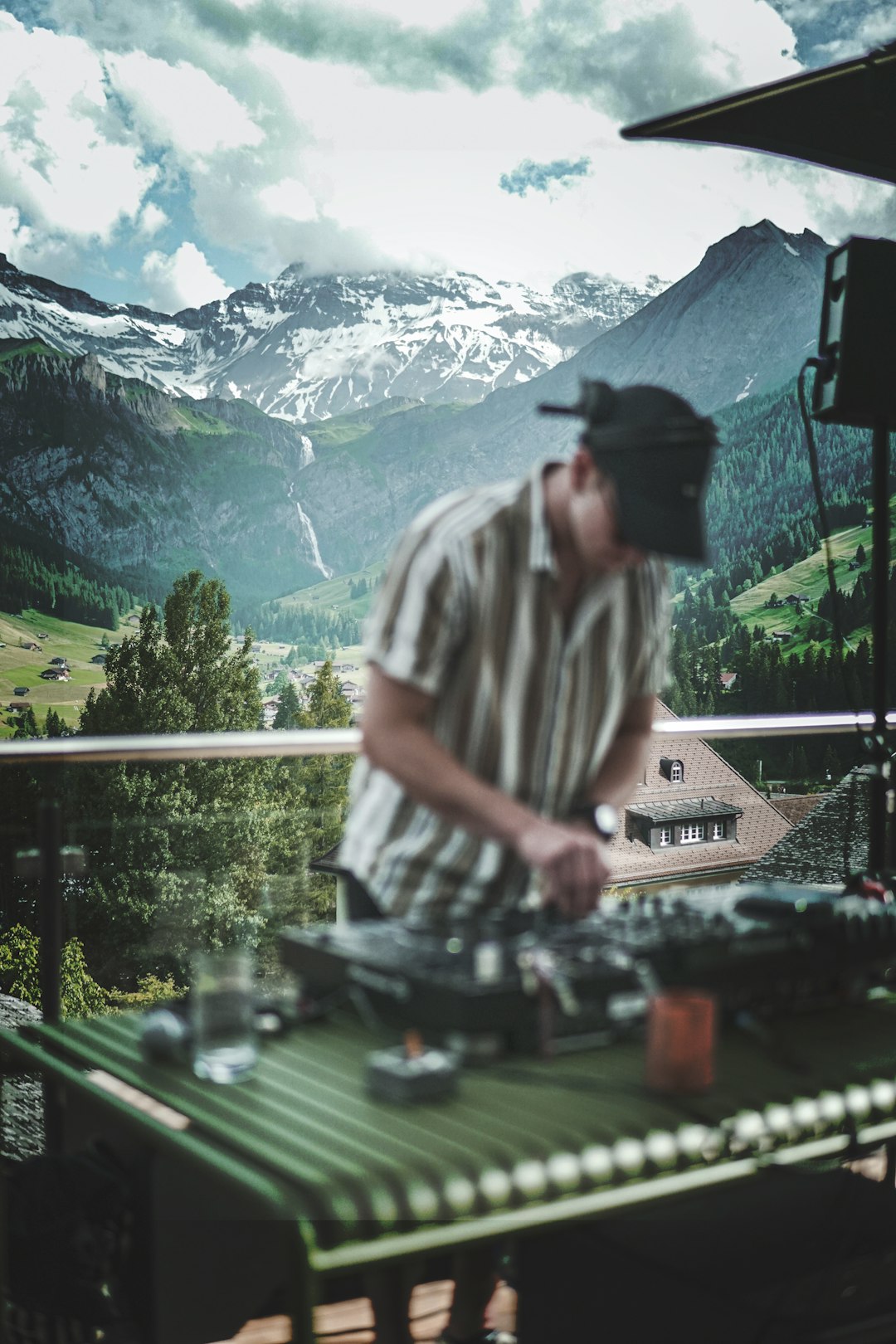 man in white and black stripe shirt standing near green trees and mountains during daytime