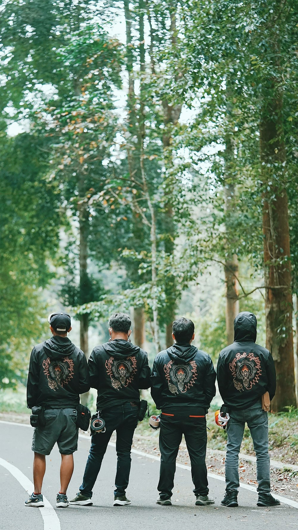 groupe de personnes en vestes noires et brunes debout dans la forêt pendant la journée