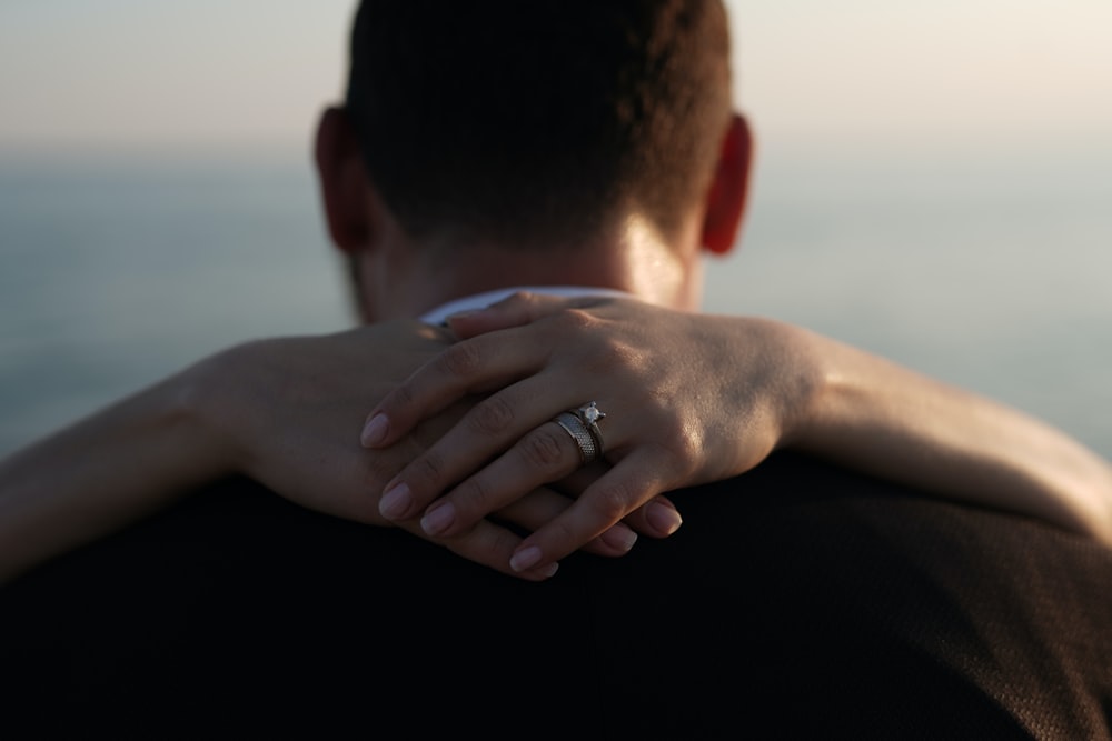 a man and woman embracing each other with the ocean in the background