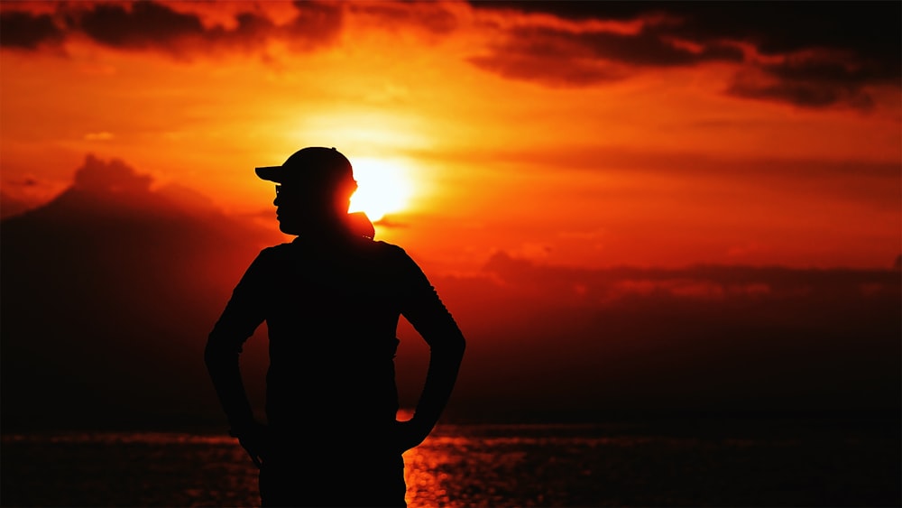 silhouette of man wearing hat during sunset