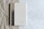 A spiral-bound notebook rests on a surface that transitions from crumpled brown paper to smooth white marble. The notebook's cover is a muted beige with a subtle design featuring a tree, and the initials 'SK' are embossed at the bottom corner.