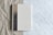 A spiral-bound notebook rests on a surface that transitions from crumpled brown paper to smooth white marble. The notebook's cover is a muted beige with a subtle design featuring a tree, and the initials 'SK' are embossed at the bottom corner.