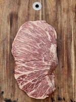 Close-up of a juicy ribeye steak with marbled fat on a wooden cutting board.