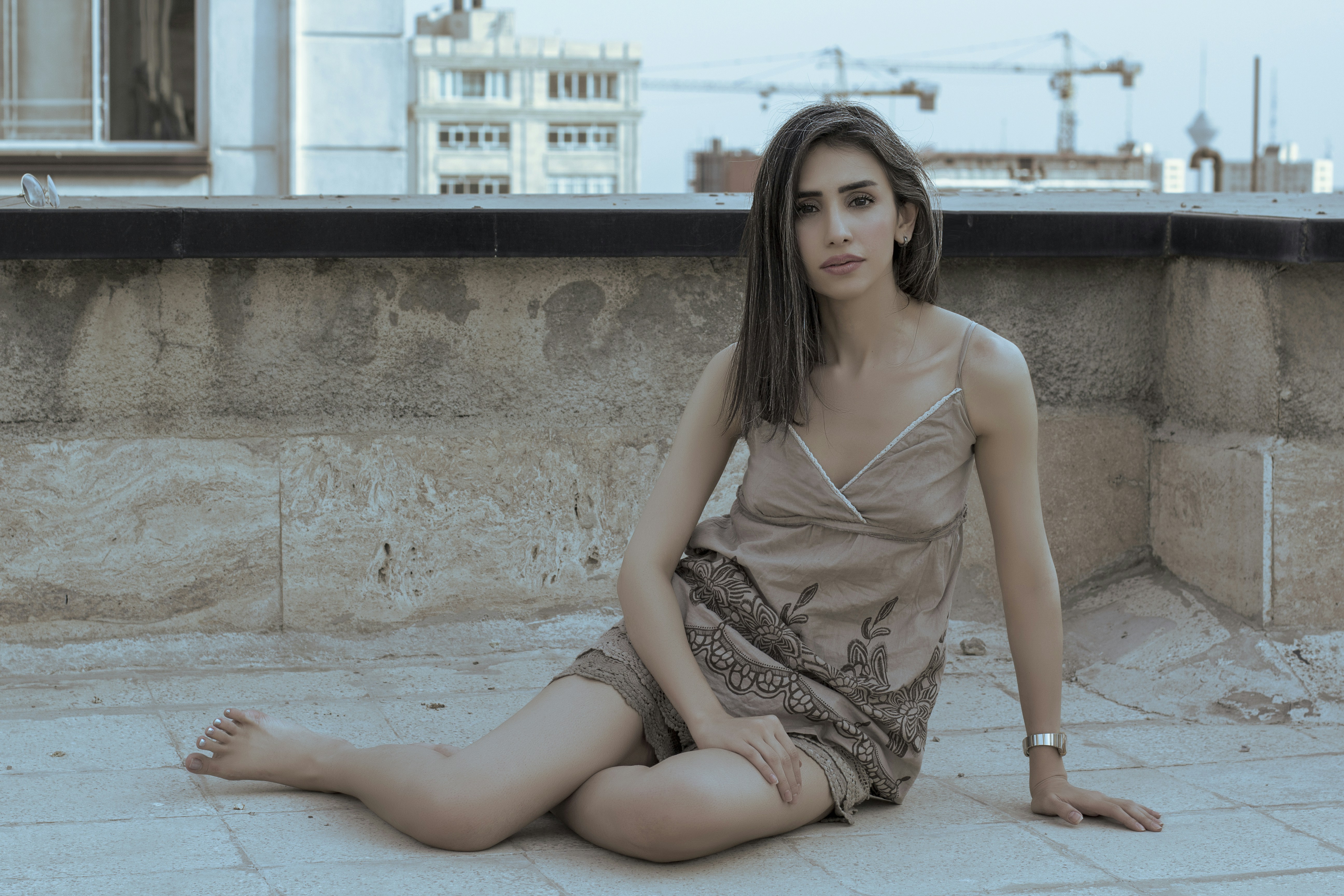 woman in brown and white spaghetti strap dress sitting on concrete floor