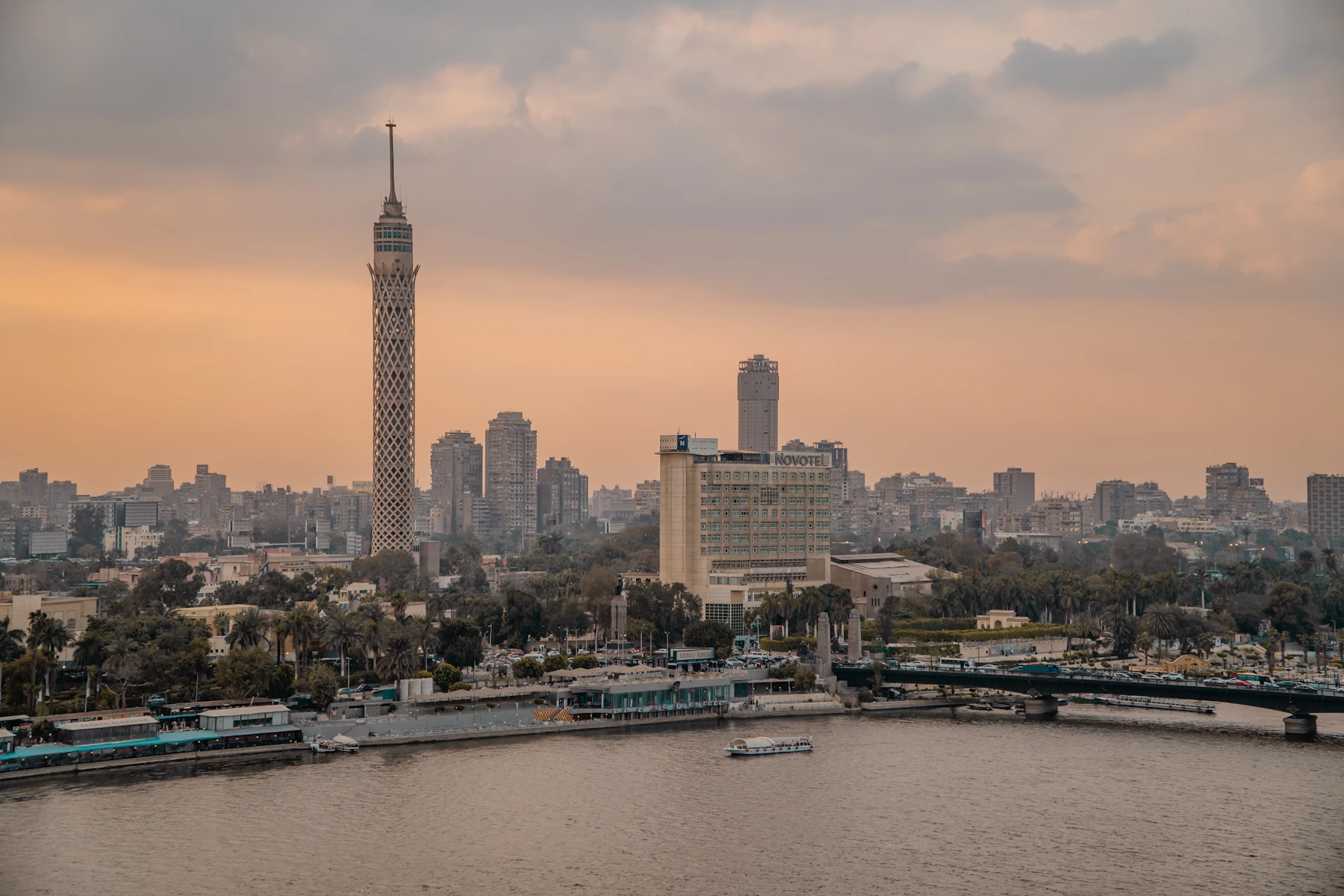 A white and blue boat moves along the Nile with Cairo buildings behind.