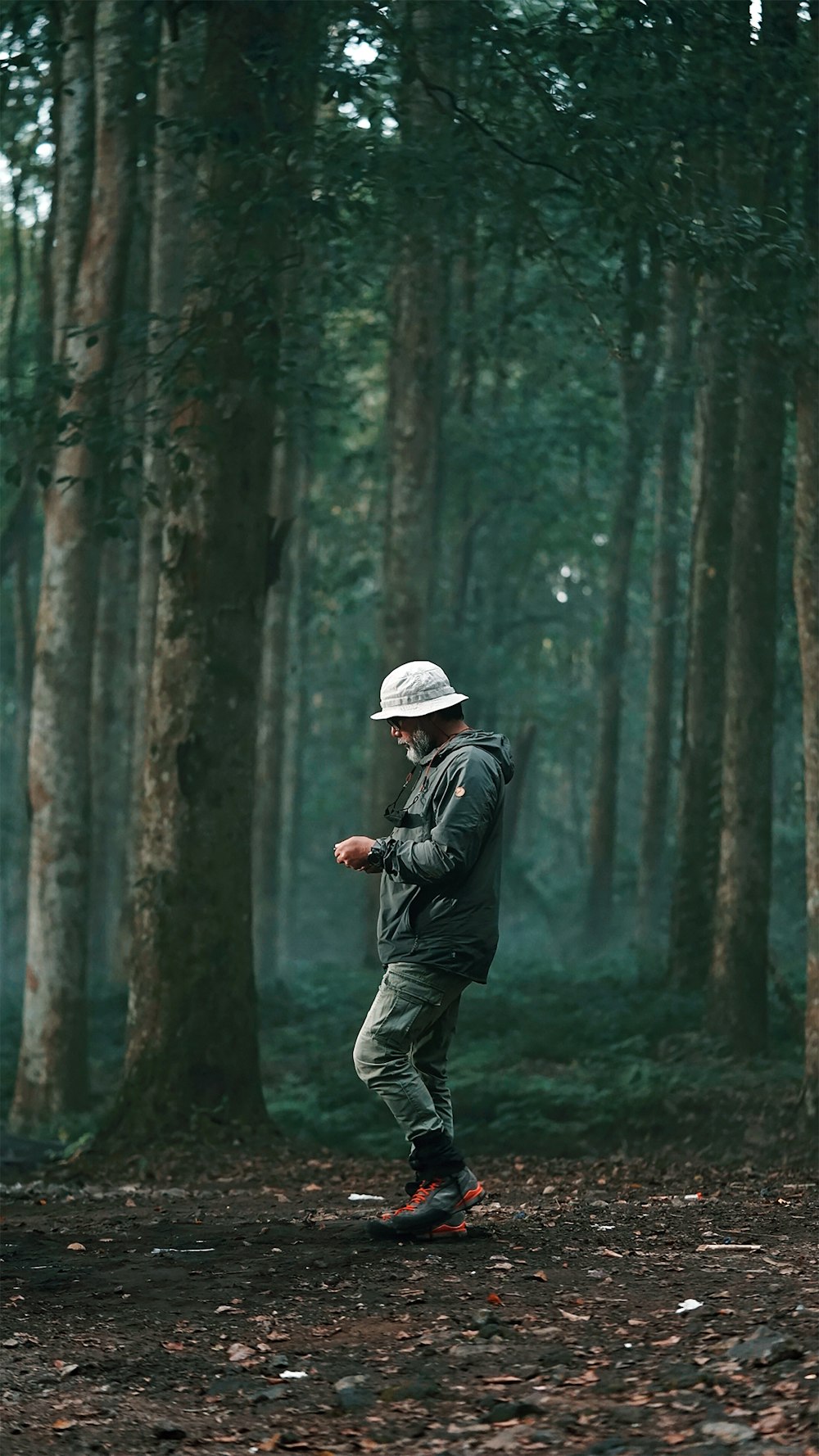 man in black jacket and gray pants standing in forest