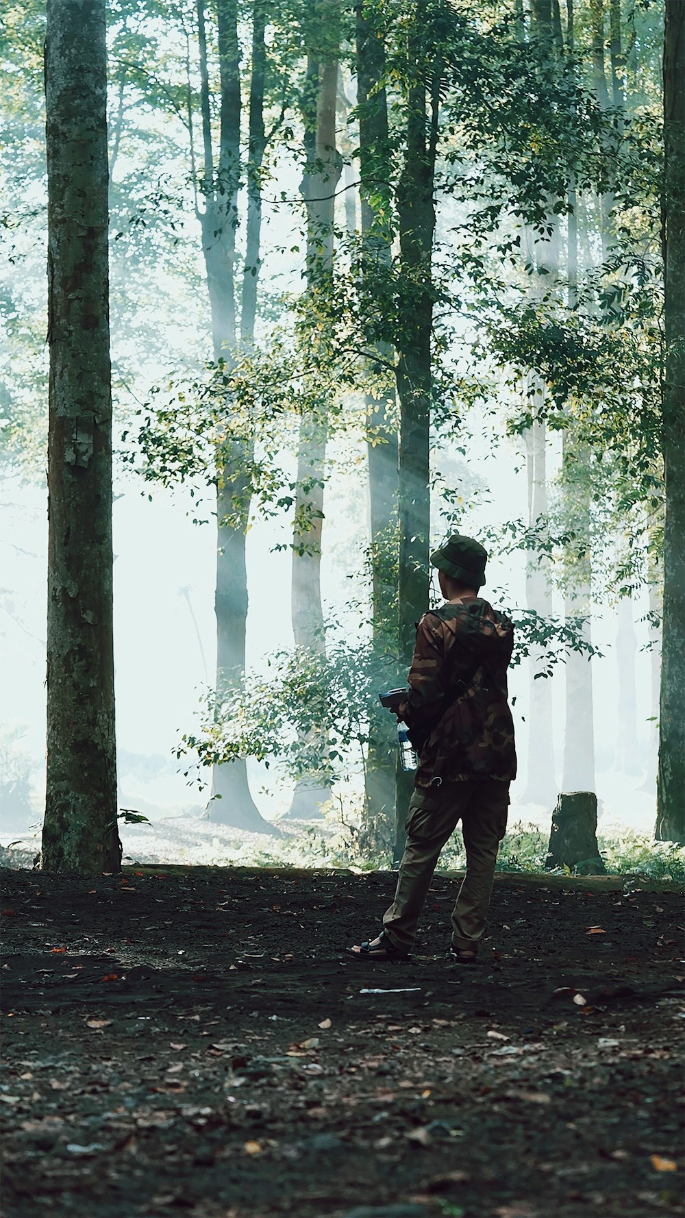 man in black jacket and pants standing near trees