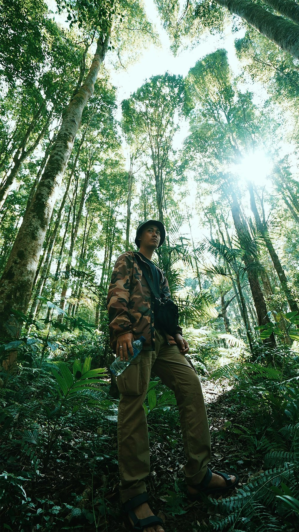 woman in black jacket and green pants standing in the middle of the forest during daytime