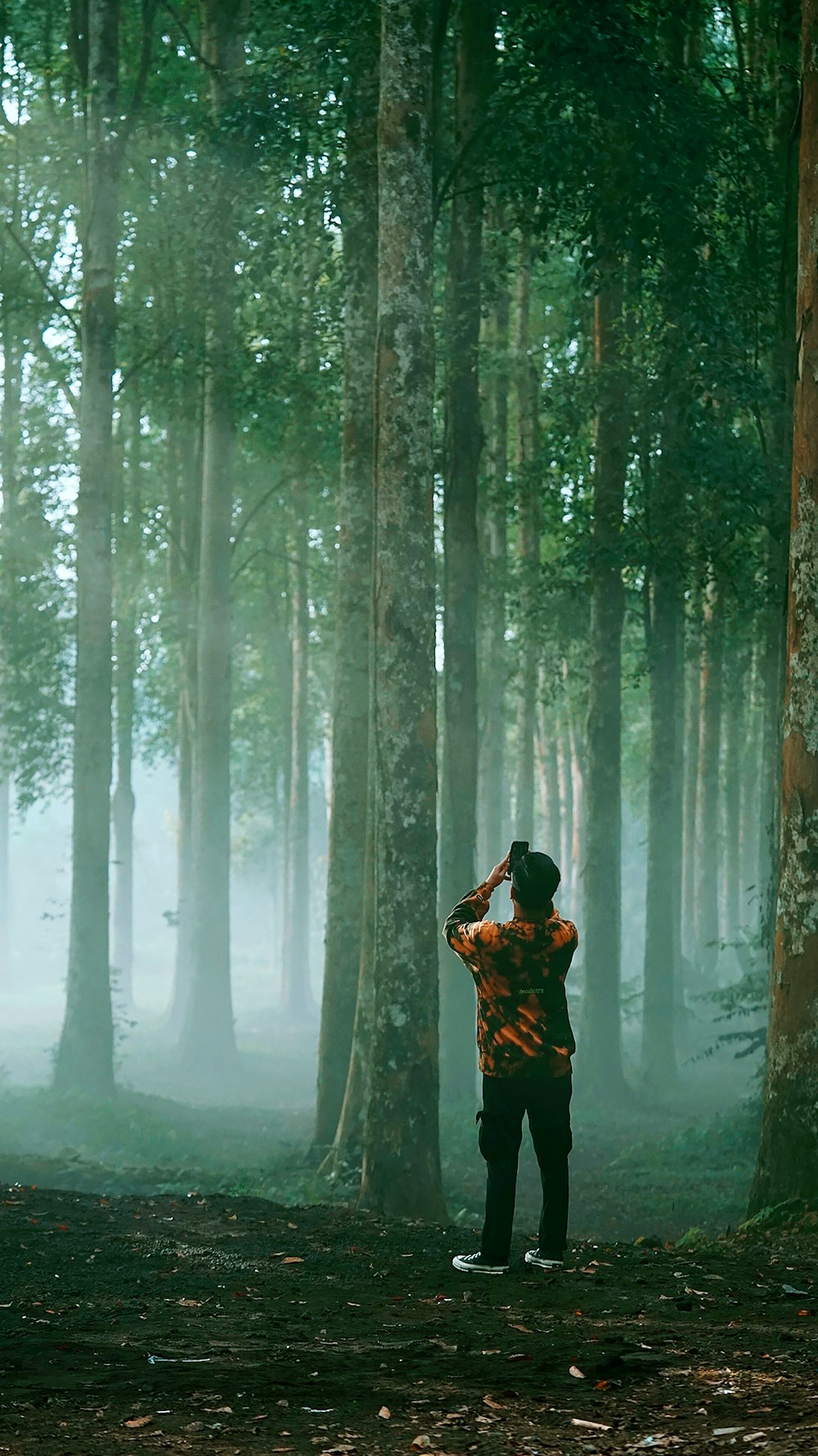 man in black jacket standing in the woods