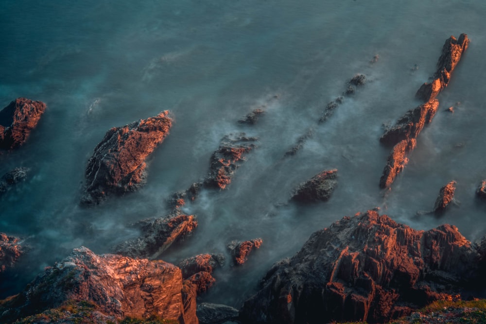 brown rock formation on body of water during daytime