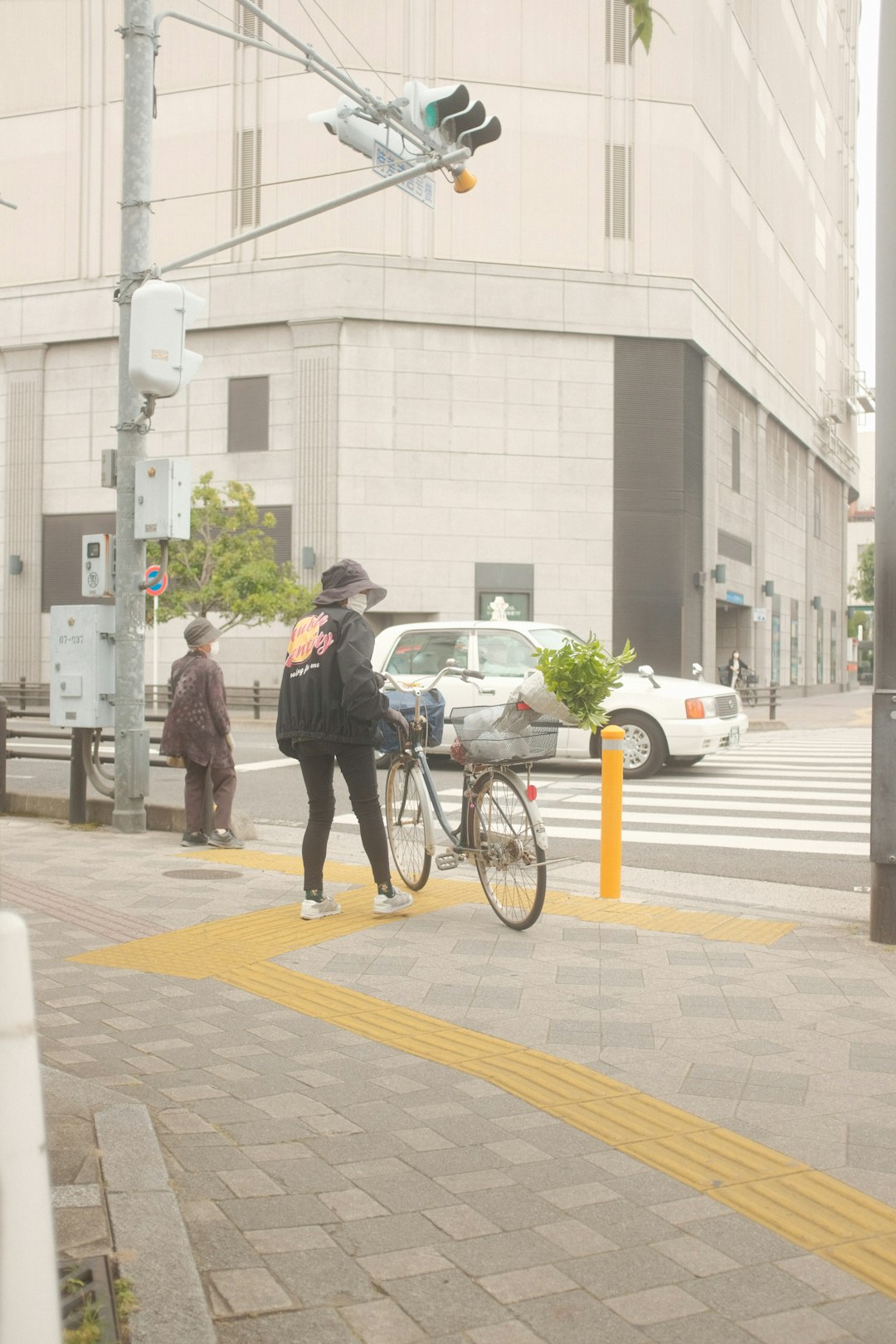 man in black suit jacket and black pants standing beside black bicycle during daytime