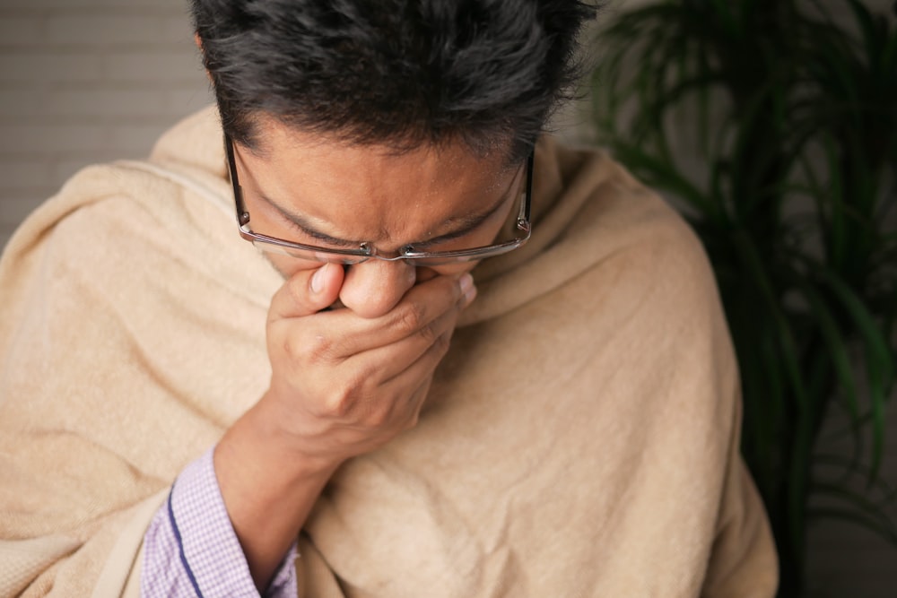 Mann im braunen Pullover mit schwarz gerahmter Brille