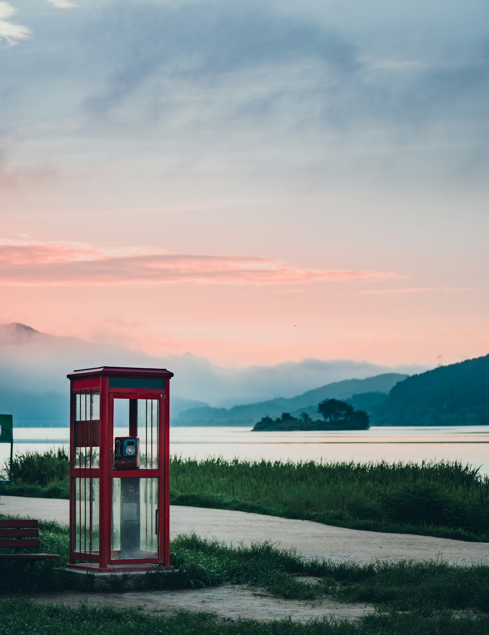 red telephone booth on lake side during daytime
