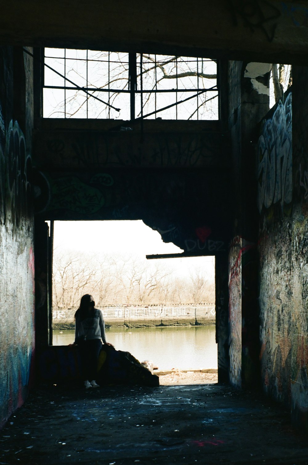 silhouette of person sitting on window during daytime